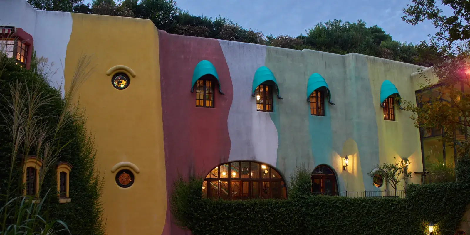 The colorful, ivy-covered exterior facade of the Ghibli Museum in Mitaka at dusk