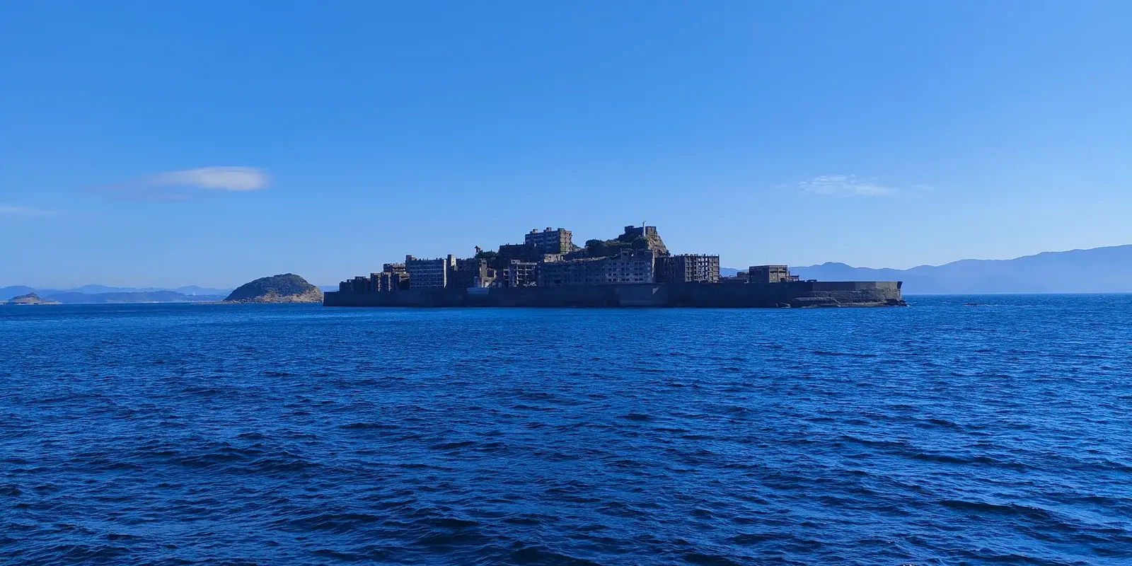 Gunkanjima (Hashima Island) seen from the sea, its ruined concrete apartment blocks giving it a battleship-like silhouette