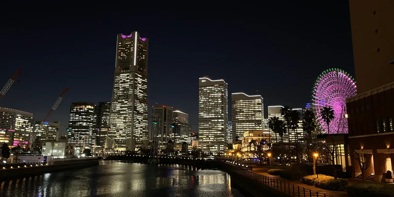 The Minato Mirai skyline at night, with Landmark Tower and the Cosmo World Ferris wheel lit up above the harbor canal