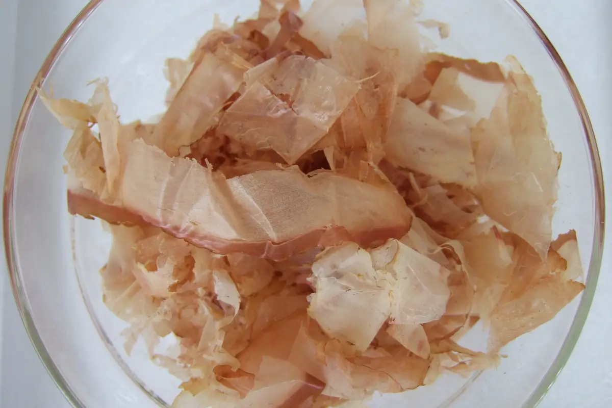 A glass bowl heaped with thin, pale pink shavings of dried bonito