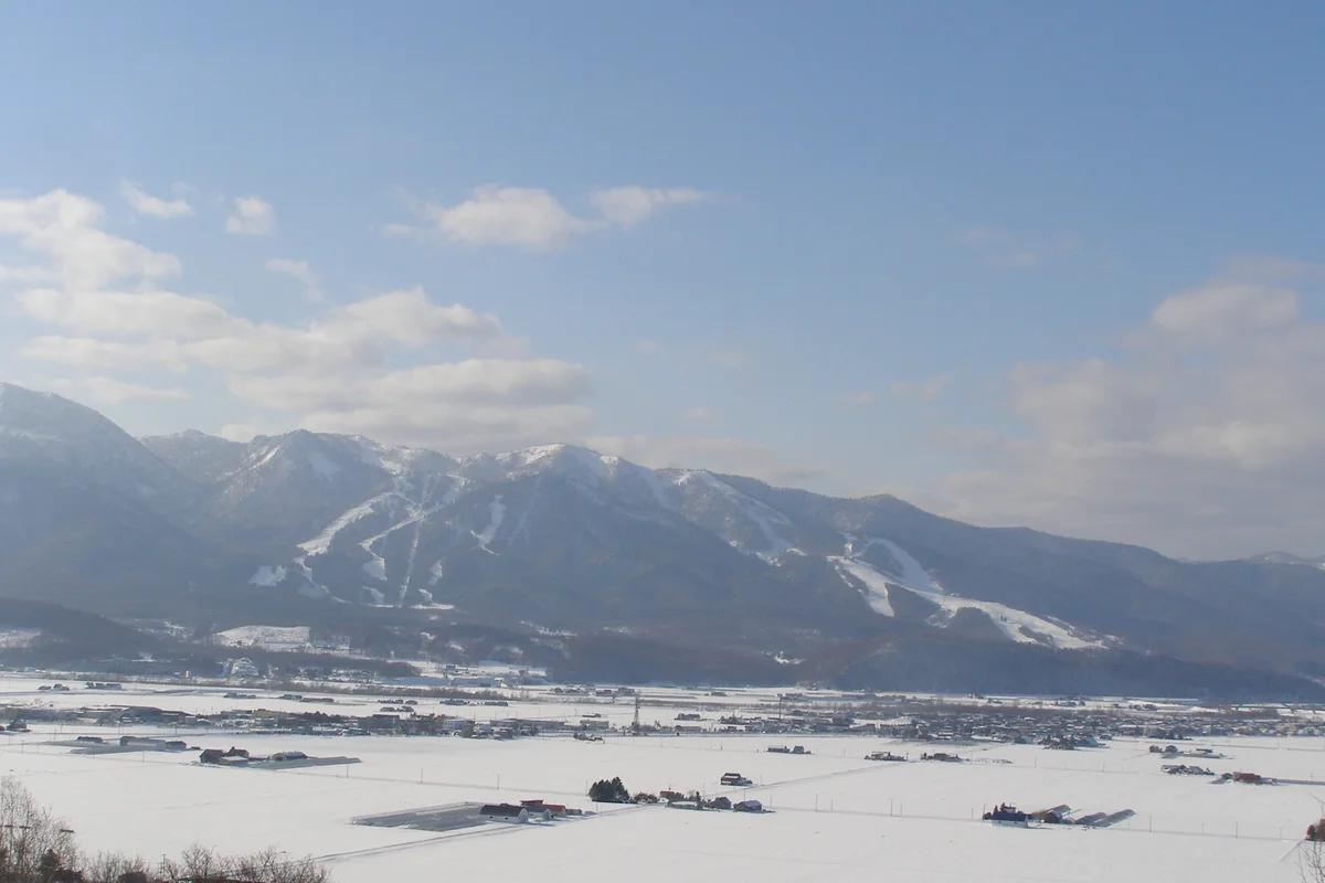 Distant view across a snow-covered valley of Furano's ski slopes cut into the mountainside