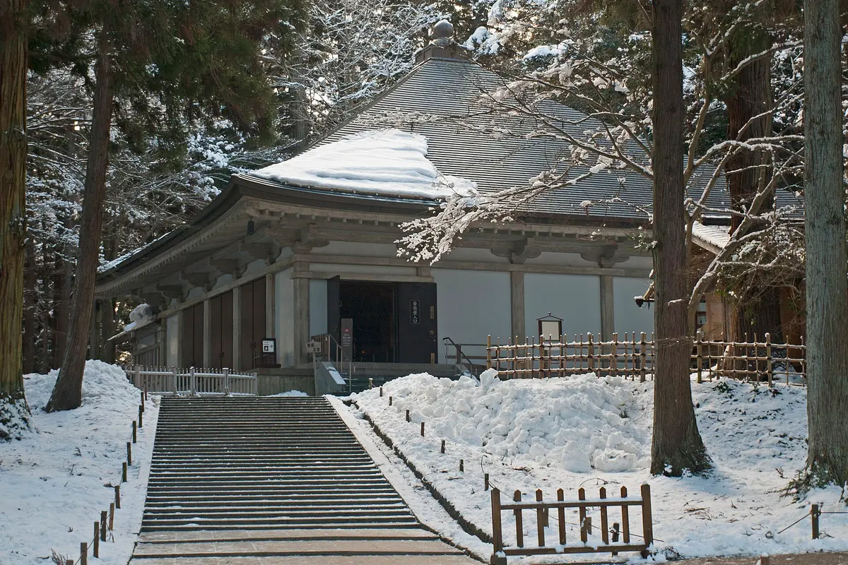 The modern shelter hall at Chuson-ji that houses the Golden Hall, seen under snow from the foot of its stone steps