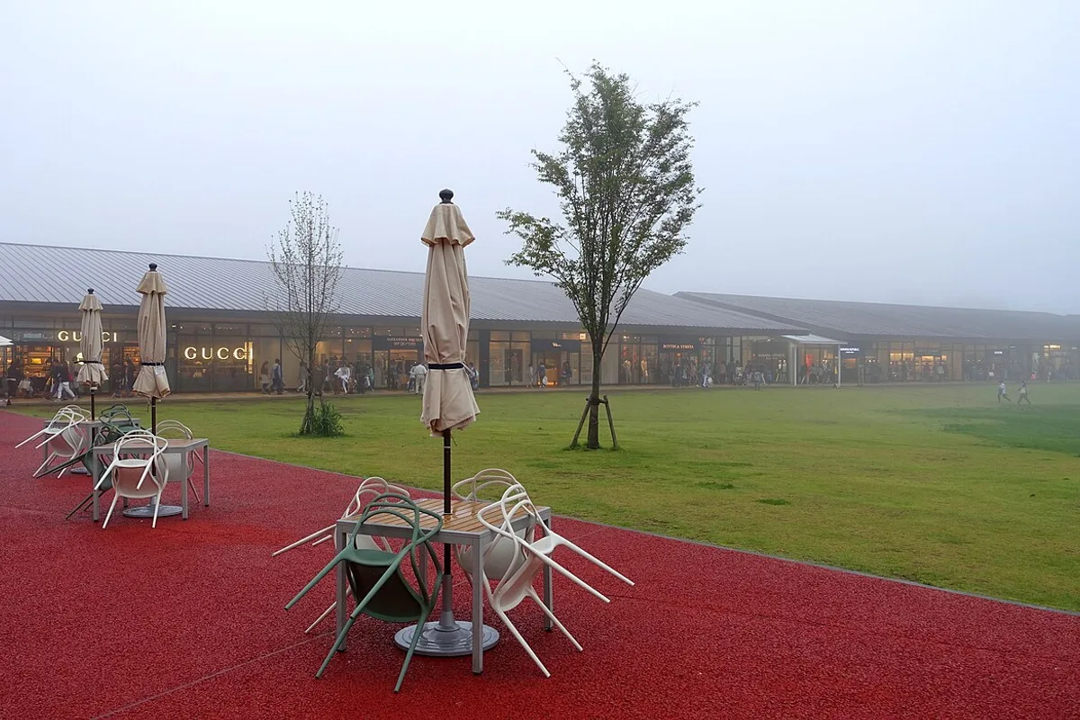 Open lawns and outdoor seating between the outlet stores at Karuizawa Prince Shopping Plaza on a misty evening