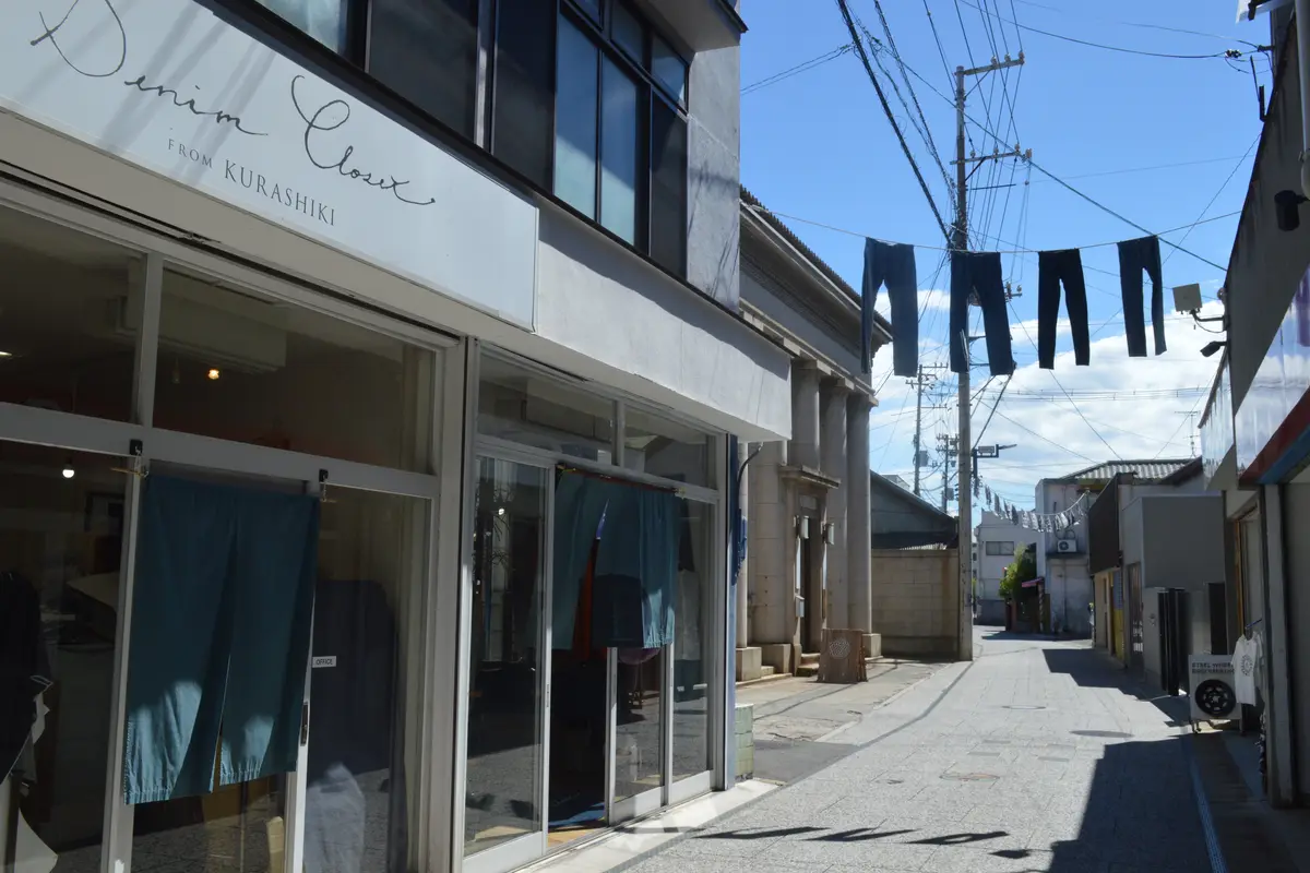 Indigo denim hung on a line high above an empty street on Jeans Street in the Kojima district of Kurashiki, beside a shop signed Denim Closet from Kurashiki