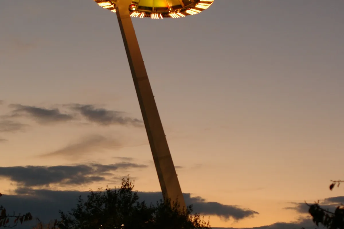 The saucer-shaped Island Fuji observation deck lit up and rising above the illuminated trees at Nabana no Sato at dusk