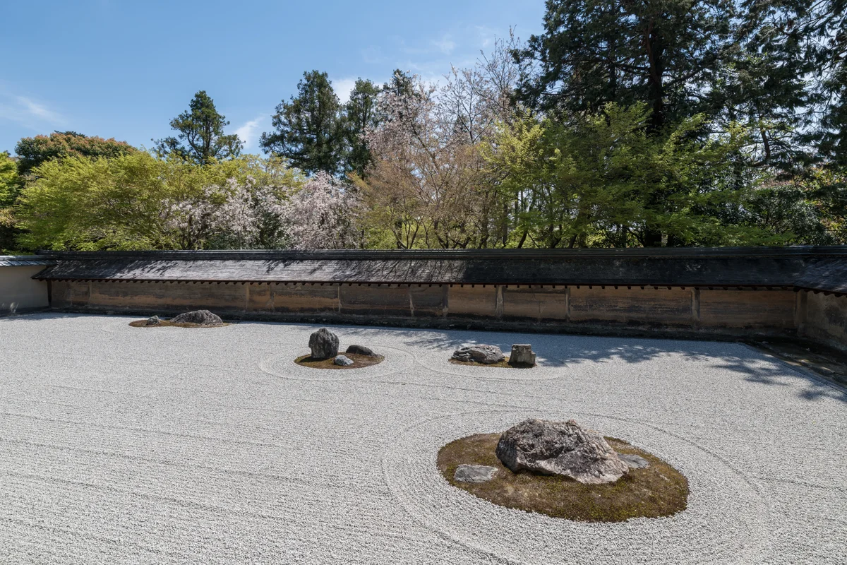 The dry rock garden at Ryoan-ji seen from the temple veranda, white gravel raked around moss-covered stone groupings