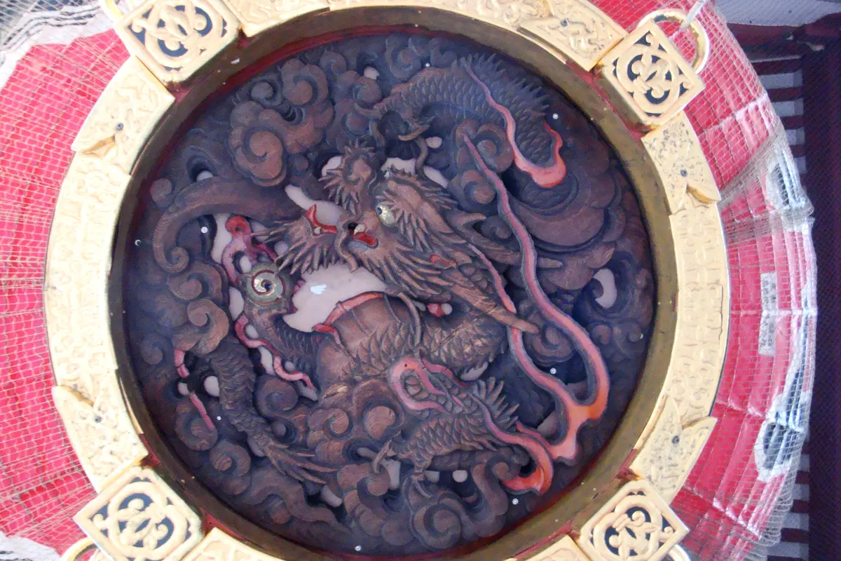 The carved wooden dragon on the underside of the great red lantern at Senso-ji's Thunder Gate, set inside a gilded ring