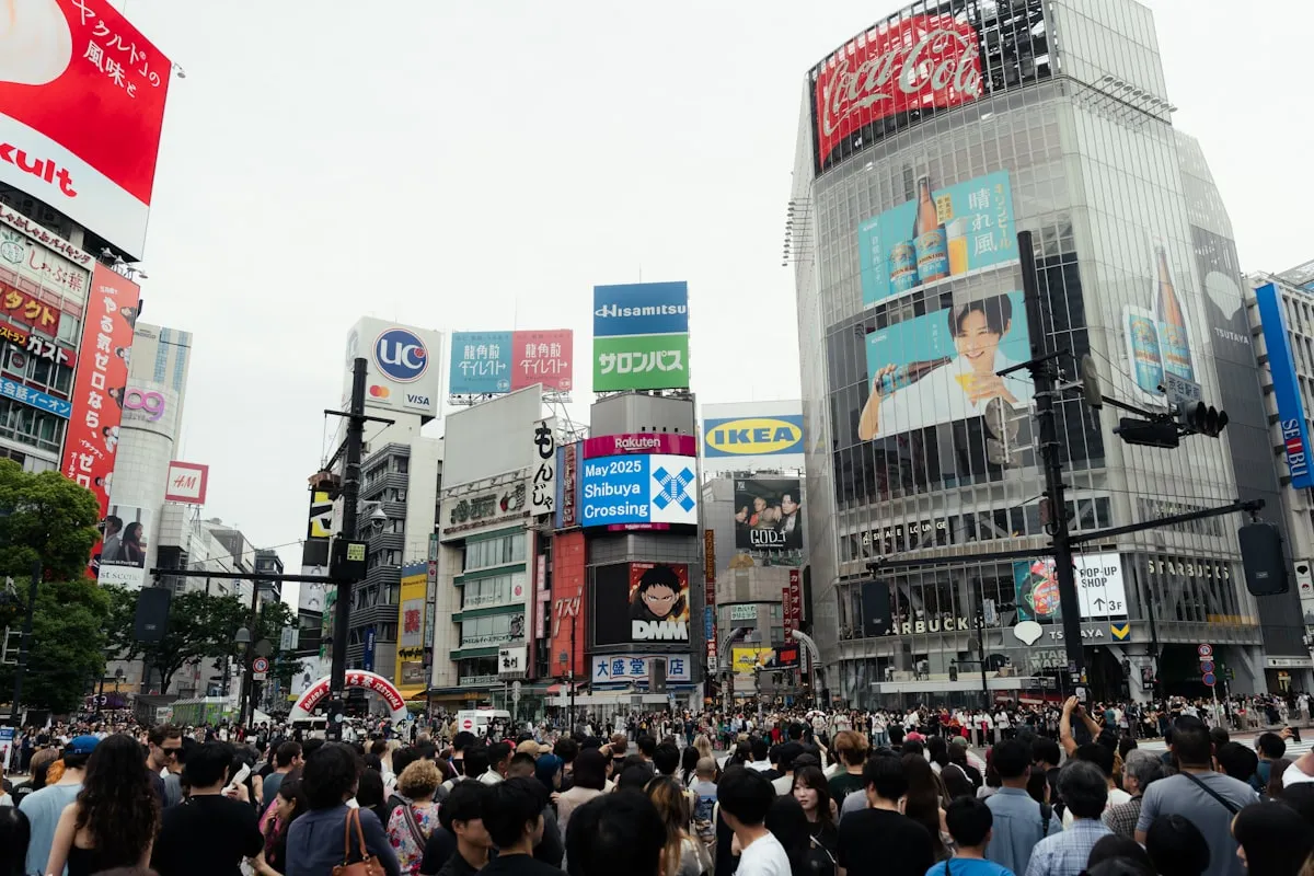 Crowds of people at Shibuya Crossing in Tokyo surrounded by billboards and neon signs