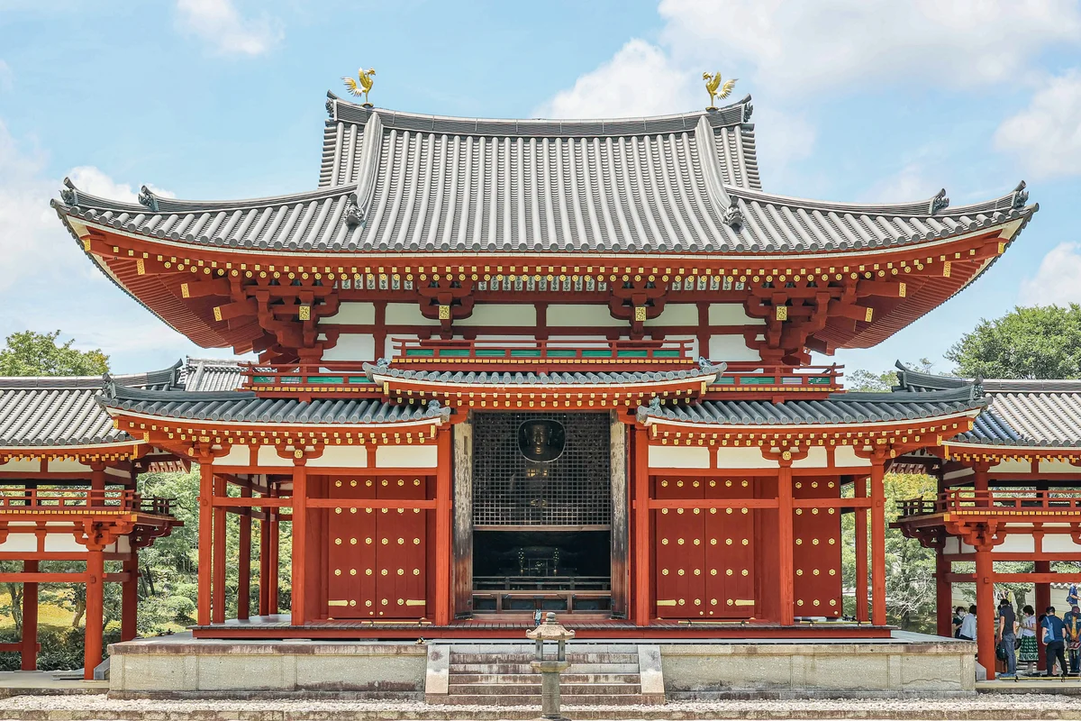 Close frontal view of Phoenix Hall's central gate, its twin gilt phoenix roof ornaments catching the light above the lattice doors that frame the Amida Buddha statue inside