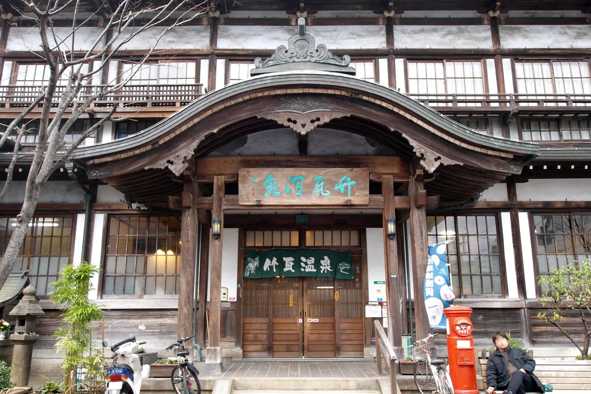 The karahafu roof and wooden entrance of Takegawara Onsen, a historic public bathhouse in Beppu's old downtown