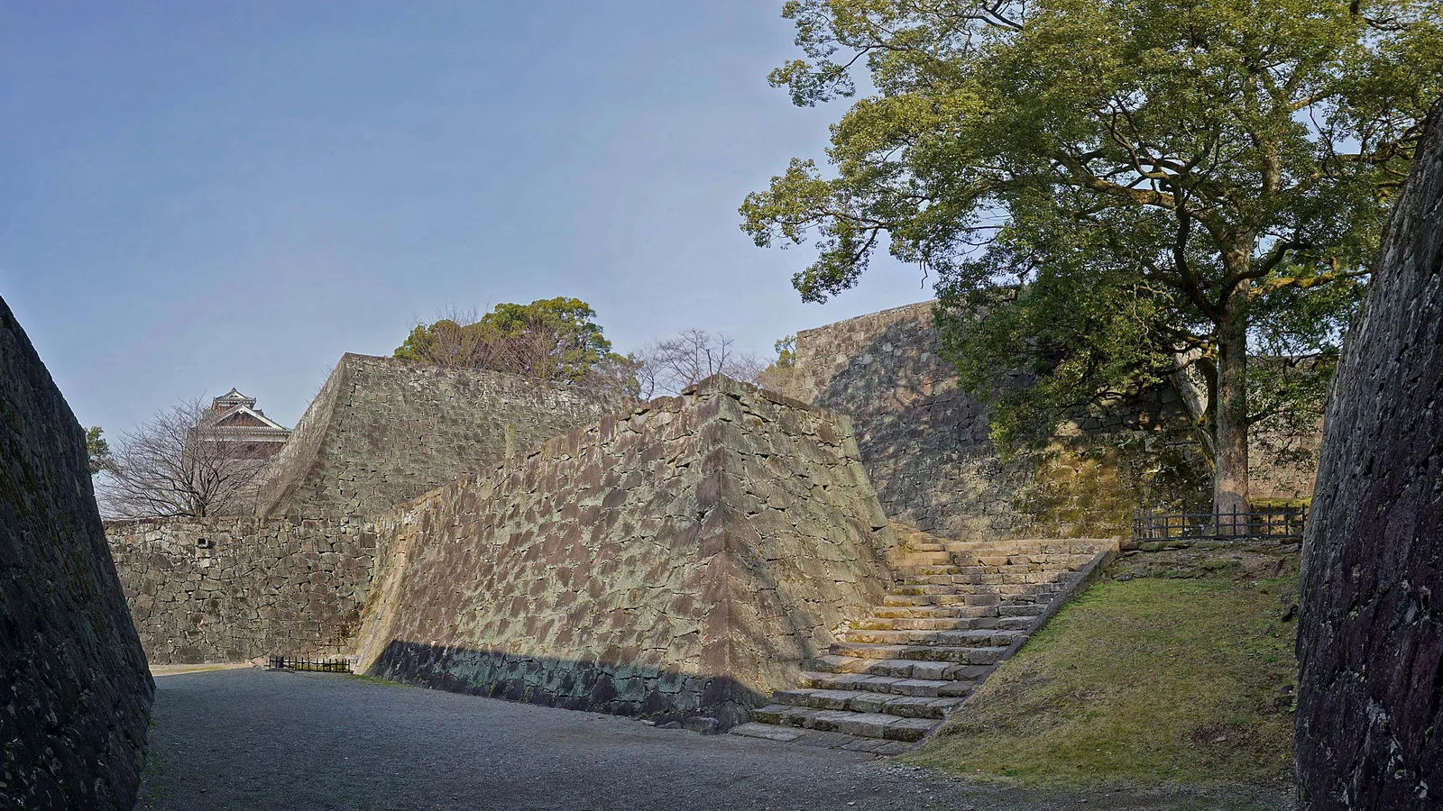The reconstructed main keep of Kumamoto Castle rising above stone walls under restoration
