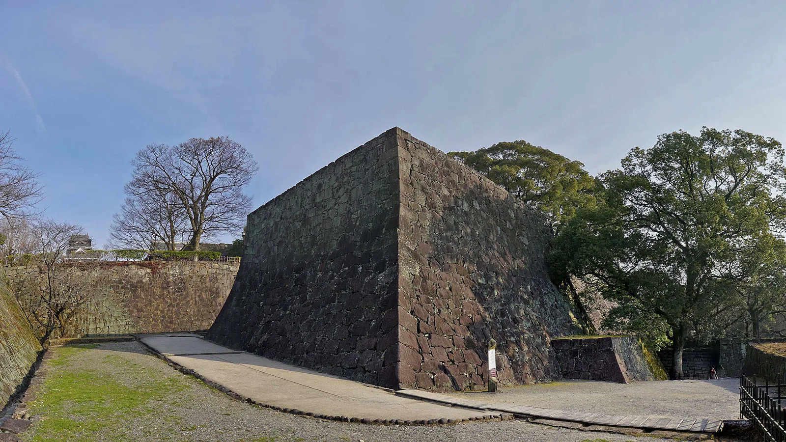 A steeply curved stone wall of Kumamoto Castle, gentle at the base and near-vertical at the top, built so it cannot be climbed