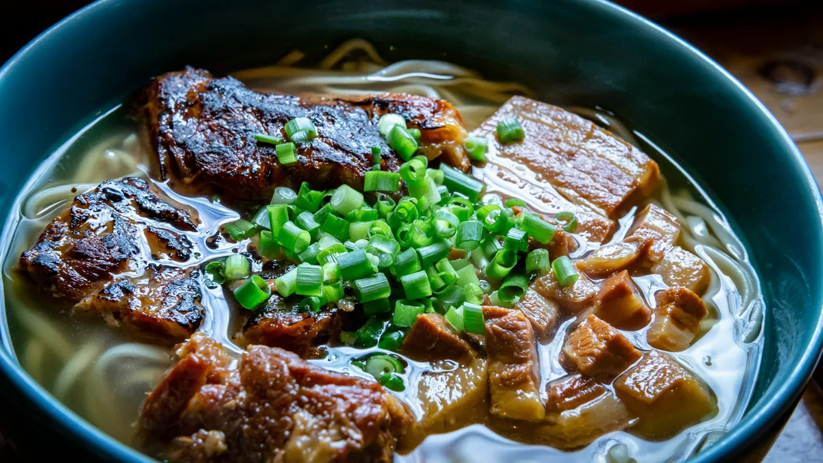 A bowl of Okinawa soba — thick wheat-flour noodles in a pork-and-bonito broth, topped with simmered pork
