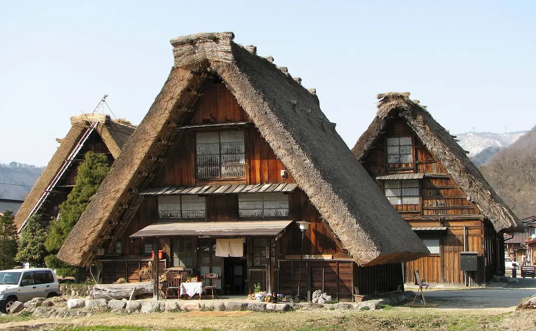 Two steep-thatched gassho-zukuri farmhouses at Shirakawa-go with a snow-capped mountain behind