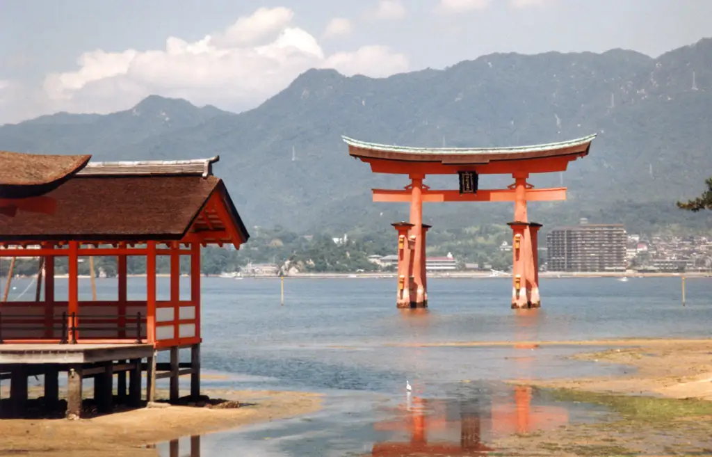 A vermilion over-water pavilion of Itsukushima Shrine on Miyajima, with the great floating torii standing out in the bay beyond