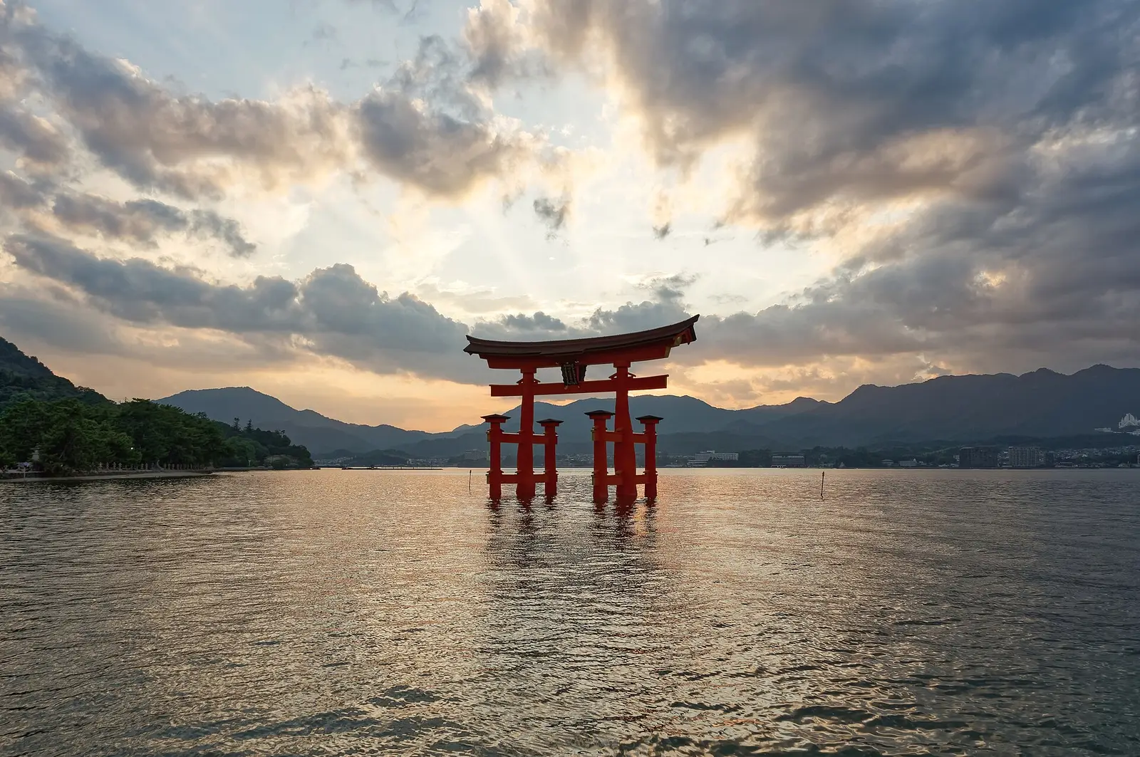 The great vermilion torii of Itsukushima Shrine standing in the sea off Miyajima at sunset, high tide reaching its feet