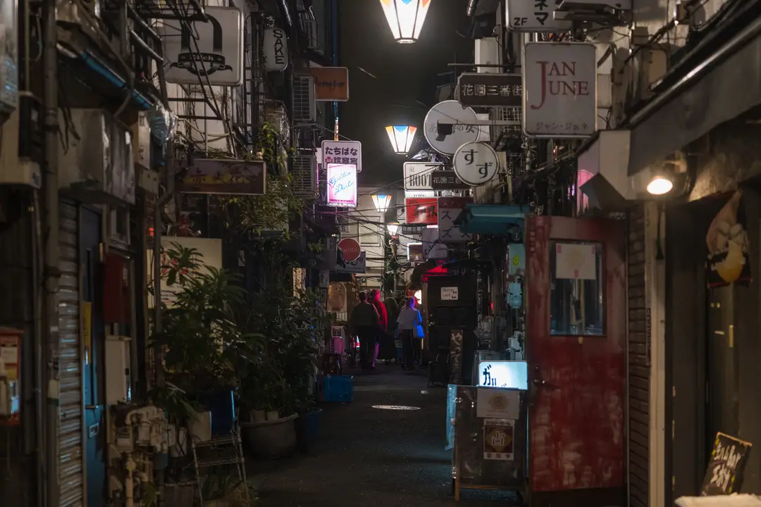 A narrow lantern-lit alley of tiny bars and izakaya glowing at night in Shinjuku's Golden Gai, Tokyo