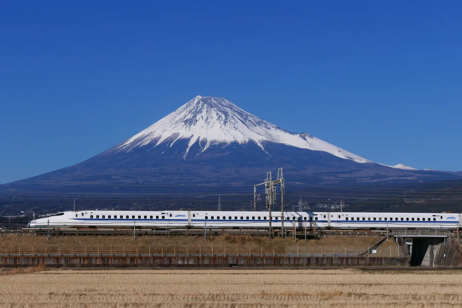 A Tokaido Shinkansen bullet train speeding past snow-capped Mount Fuji on the line that links the Tokyo and Kyoto sides of Japan