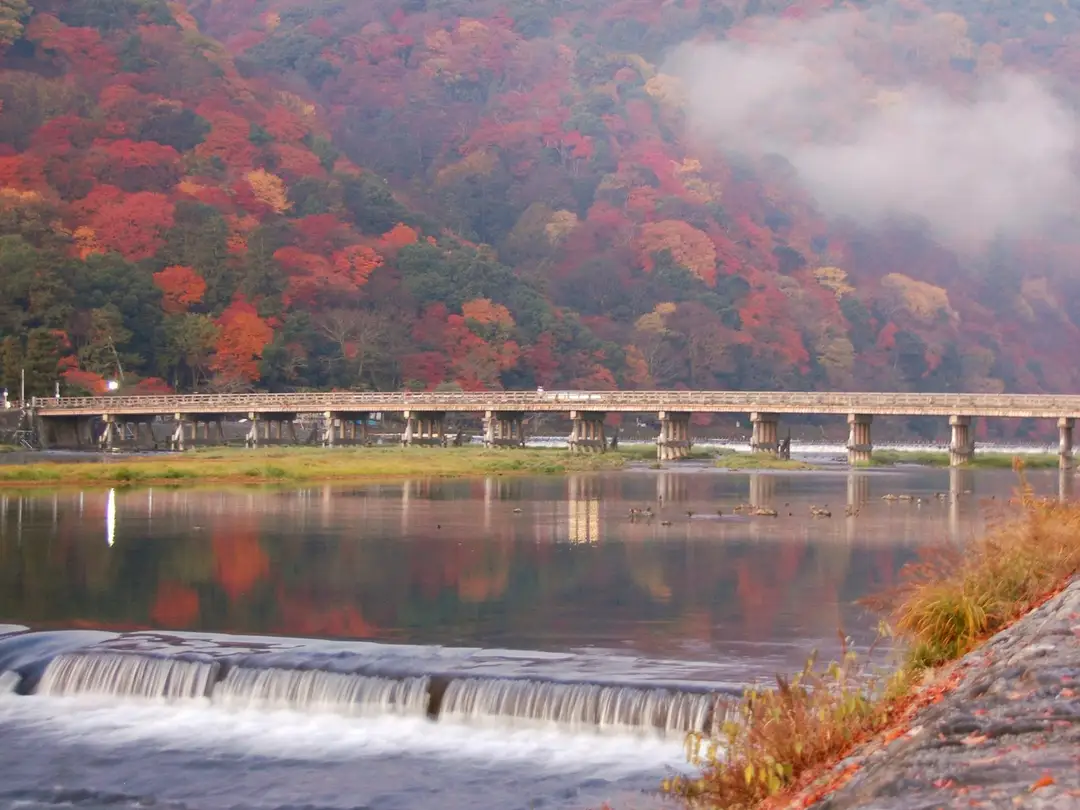 The Togetsukyo bridge over the Hozu river with the autumn-coloured Arashiyama mountainside and morning mist behind, Kyoto
