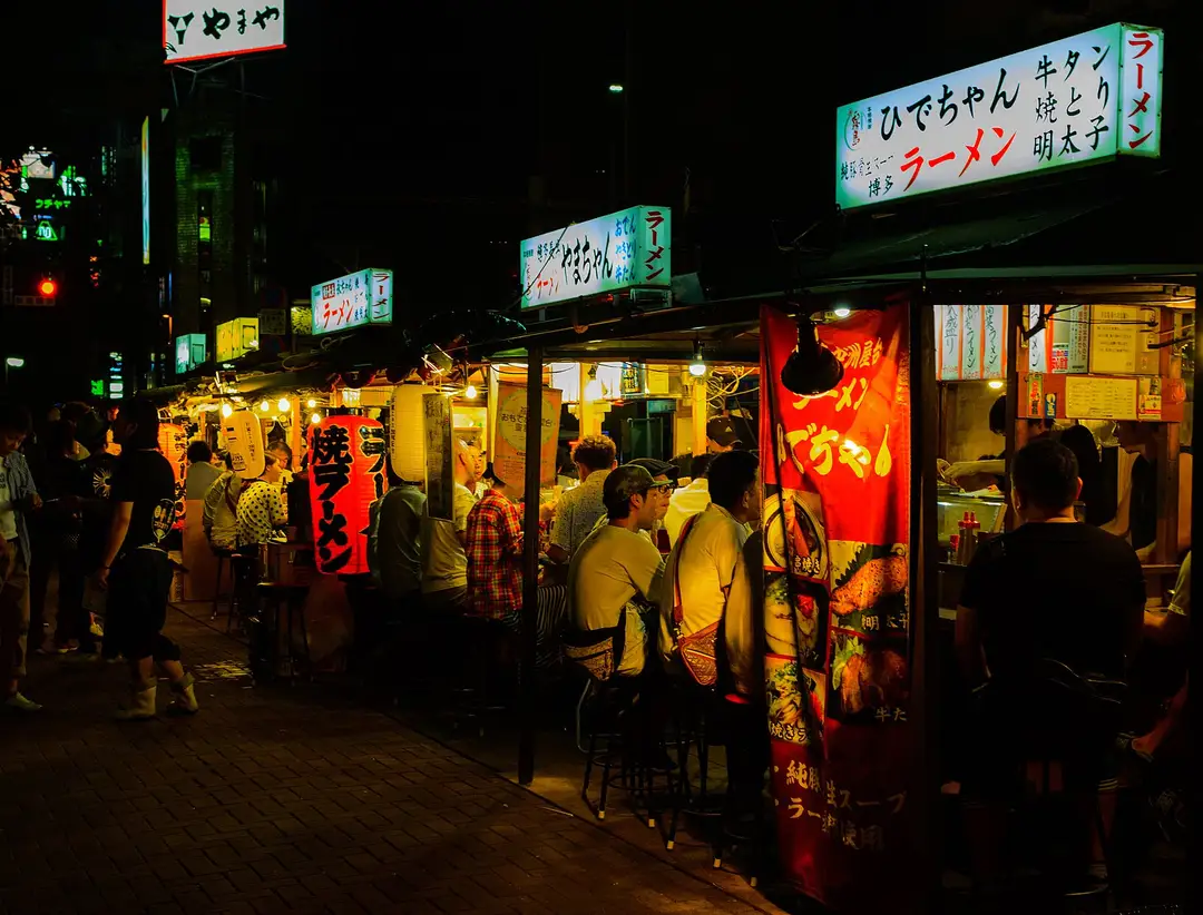 Fukuoka's open-air yatai food stalls glowing with lantern light and ramen signs at night in Nakasu
