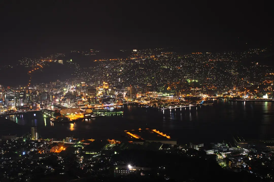 The night view of Nagasaki's city lights cupped in the dark hills around the harbour, seen from Mount Inasa