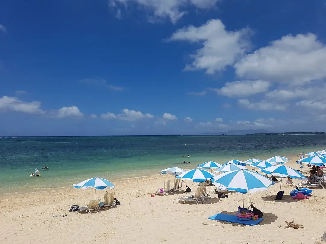 Turquoise reef water and blue-and-white beach parasols on Okinawa's central-west coast