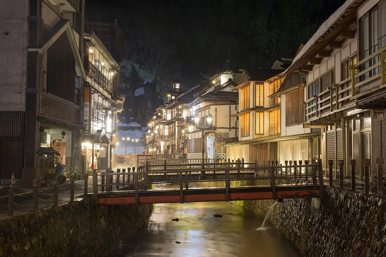 Lantern-lit wooden ryokan lining the canal at Ginzan Onsen in the evening