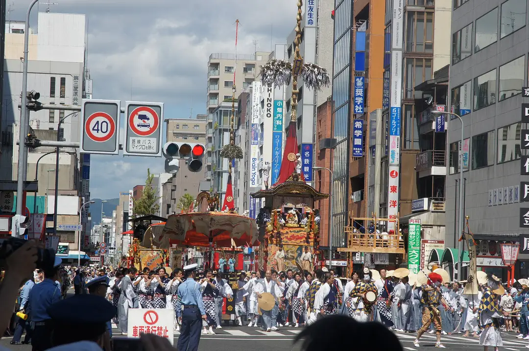 Tall wooden Gion Matsuri floats standing along a crowded downtown Kyoto street during the July festival