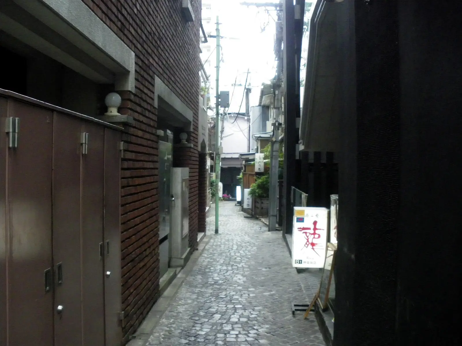 A quiet stone-paved alley off Kagurazaka-dori in Tokyo, lined with old buildings