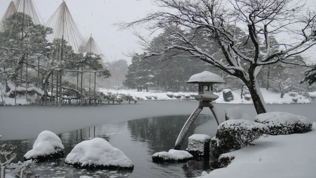 Kenrokuen garden under fresh snow in Kanazawa — the Kotojitoro stone lantern by the pond and pines held under conical yukitsuri ropes